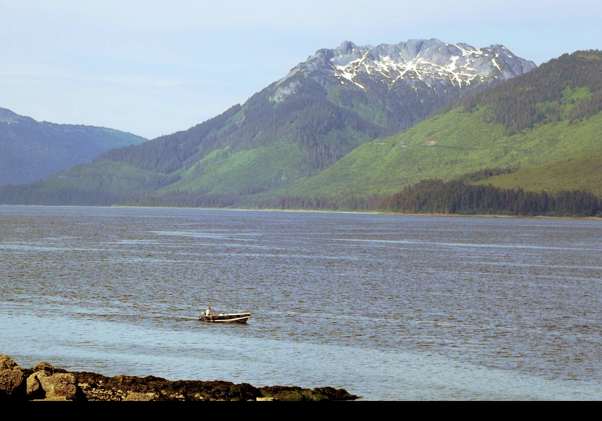 A small boat hugging the shore. The body of water is Port Frederick which drains into Icy Strait.