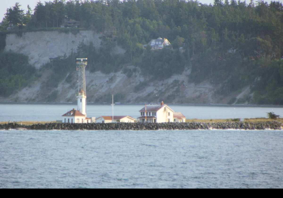 The original Point Wilson lighthouse was a wooden tower built in 1879 with a fourth-order Fresnel lens. After it deteriorated, the current 14m (46 ft) reinforced concrete octagonal tower replaced it in 1914. The Fresnel lens continues in use, though the lighthouse was automated in 1976.