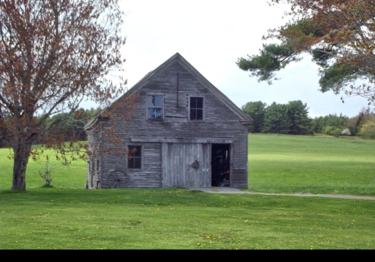 The single-story clapboard carriage house has a track-mounted sliding door, and a gable roof.