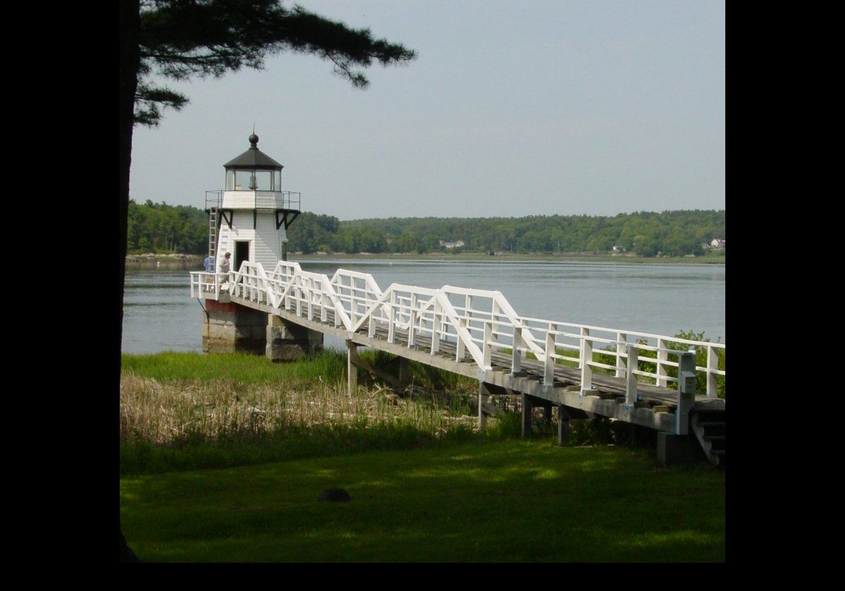Originally installed on Arrowsic Island in 1898, with an adjacent keepers cottage, Doubling Point lighthouse was moved to a granite pier offshore in the following year.  A wooden footbridge connected the lighthouse to the island.   It is an octagonal wooden tower some 23 feet high.  