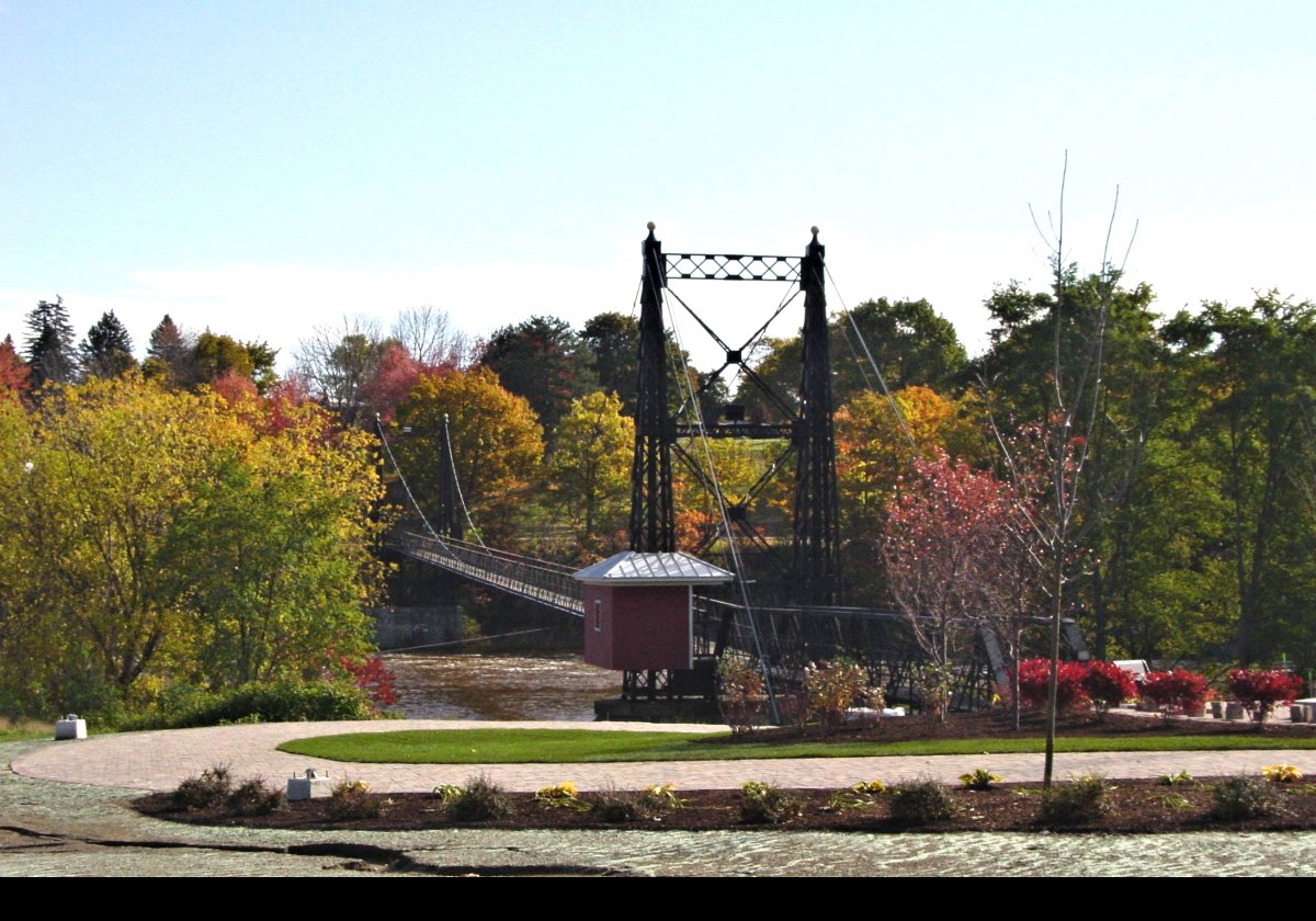 This is the Ticonic Footbridge, more commonly known as the Two Cent Bridge. It is a suspension footbridge crossing the Kennebec River between Waterville and Winslow. It is believed to be the last toll footbridge still standing in the U.S. The original (1901) bridge was destroyed in its first year by high water levels. Rebuilt in 1903, with the two cent toll that gives it its name, it has survived until today.