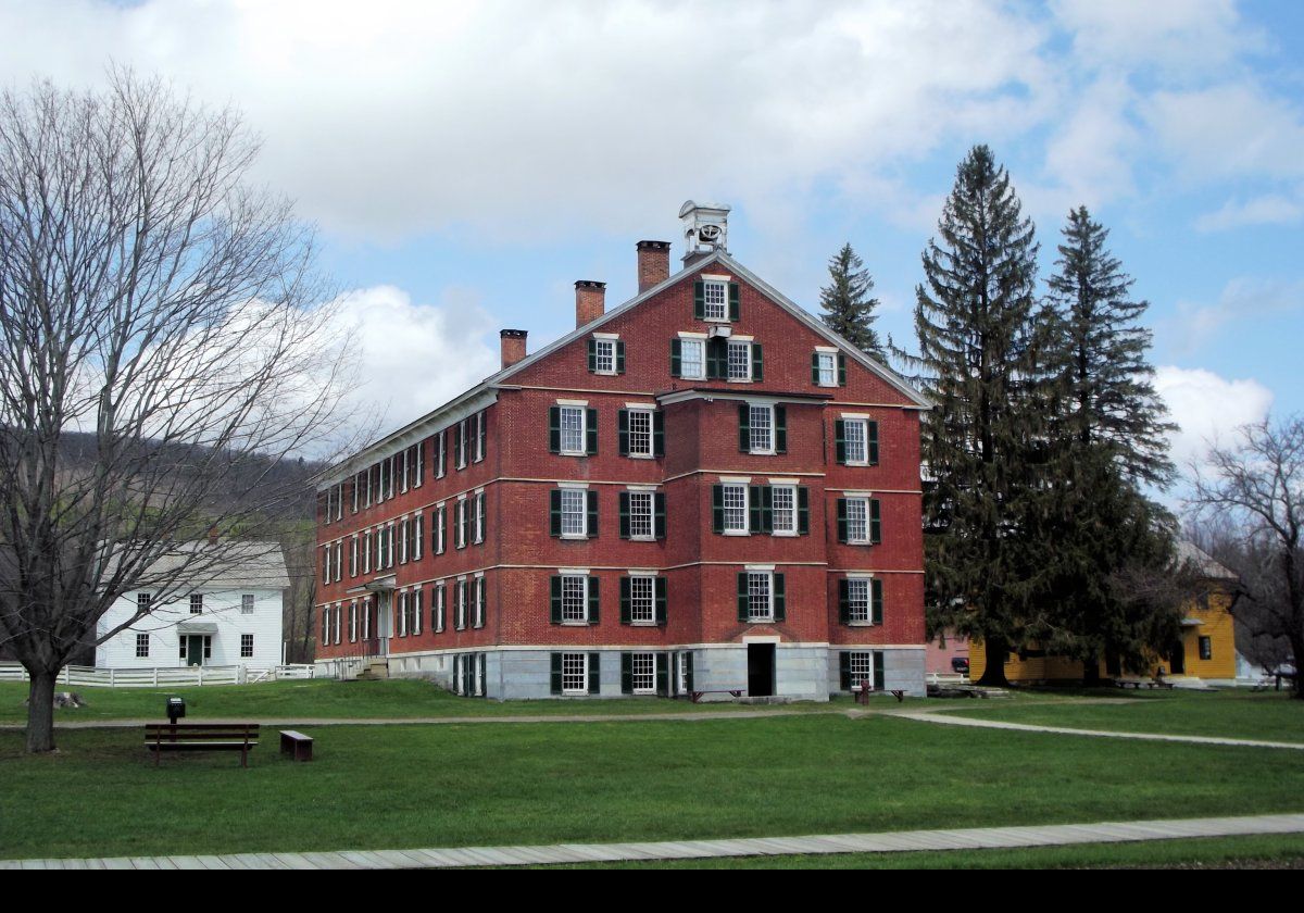 The Brick Dwelling. There are a number of pictures of the interior further in this slide show. The white building to the left is the Ministry Shop. The yellow building partially visible on the right is the Sisters' Dairy and Weave Shop.