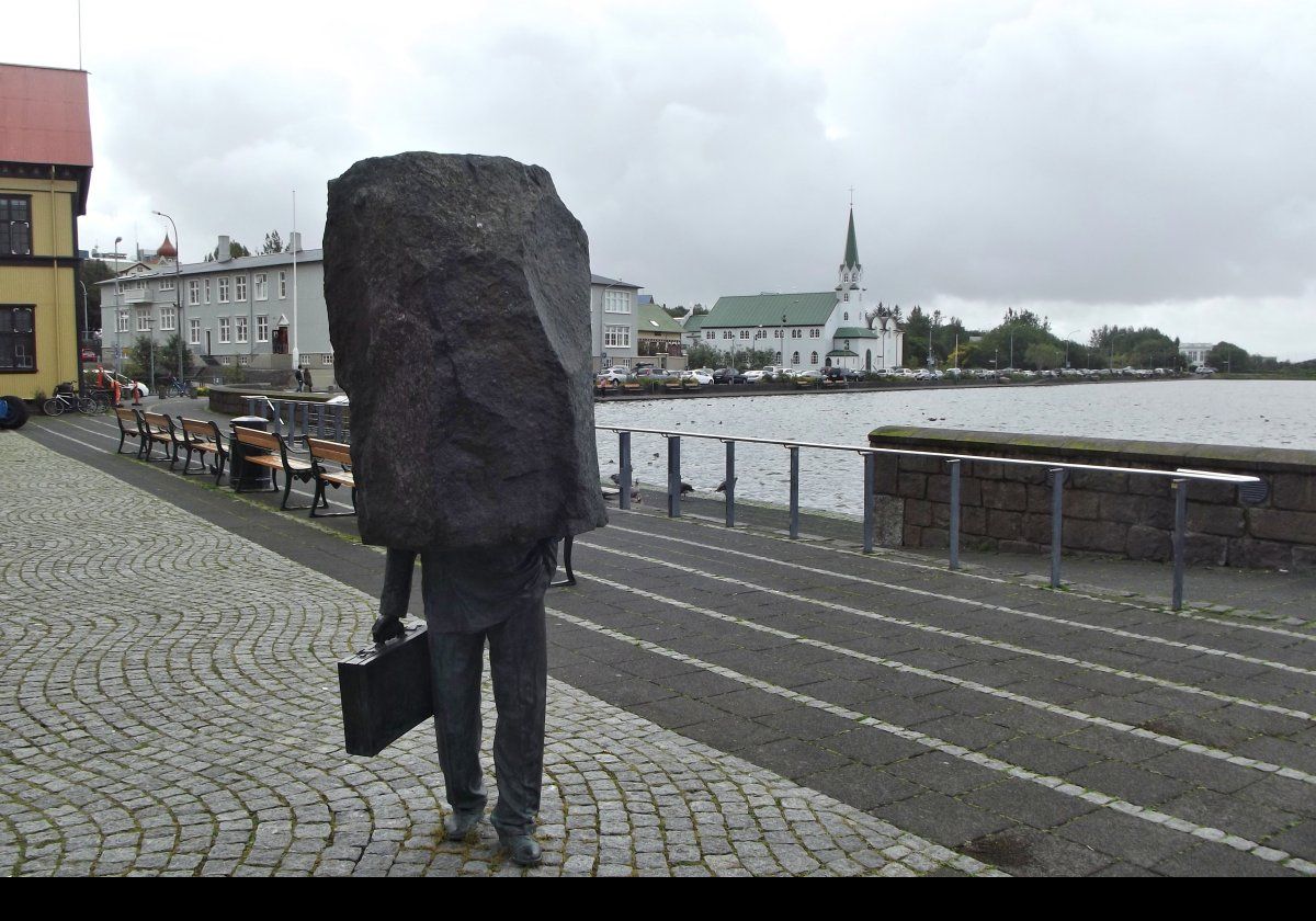 This statue titled "Monument to the Unknown Official" sits near the entrance to City Hall on the edge of the Tjörnin lake. Magnús Tómasson's sculpture, completed in 1964, shows a man in a business suit with a briefcase, but his head and upper body are encased in a stone slab.