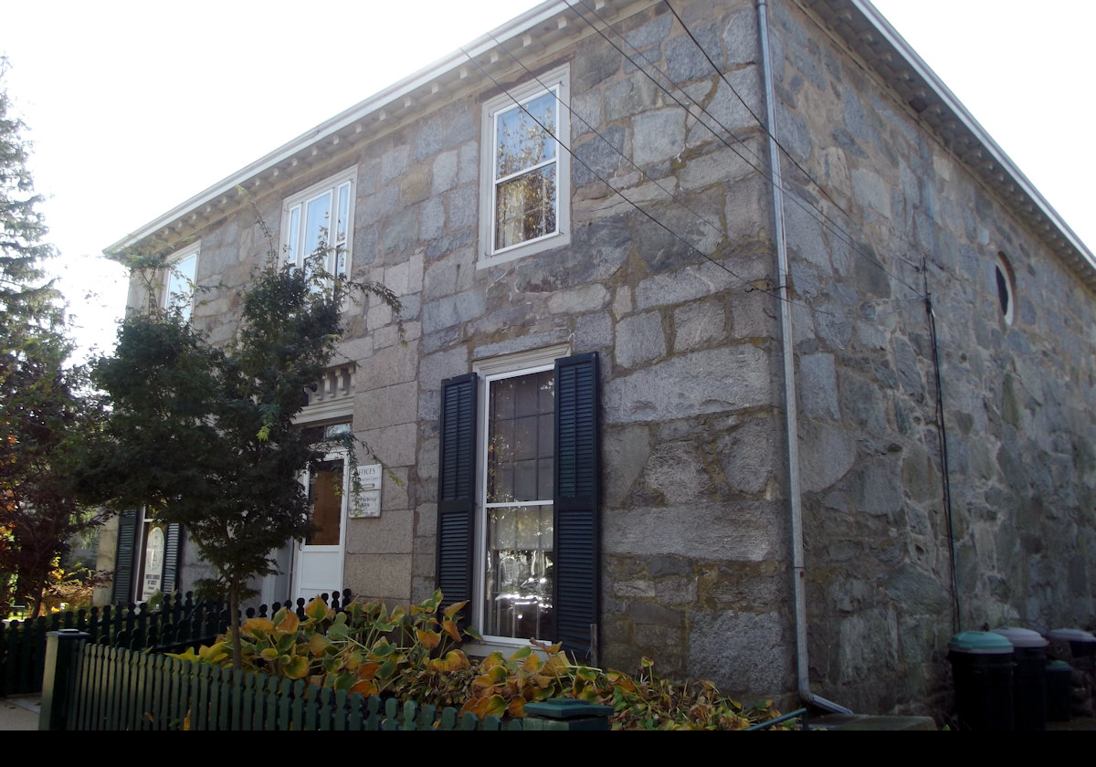 281 High Street was built in 1824 as a barn for James DeWolf. In 1850, his son William contracted Russell Warren to convert it into a house. You can see the large granite blocks that filled in the barn doors around the new front entrance. Currently, it is the parish house for the Congregational Church.