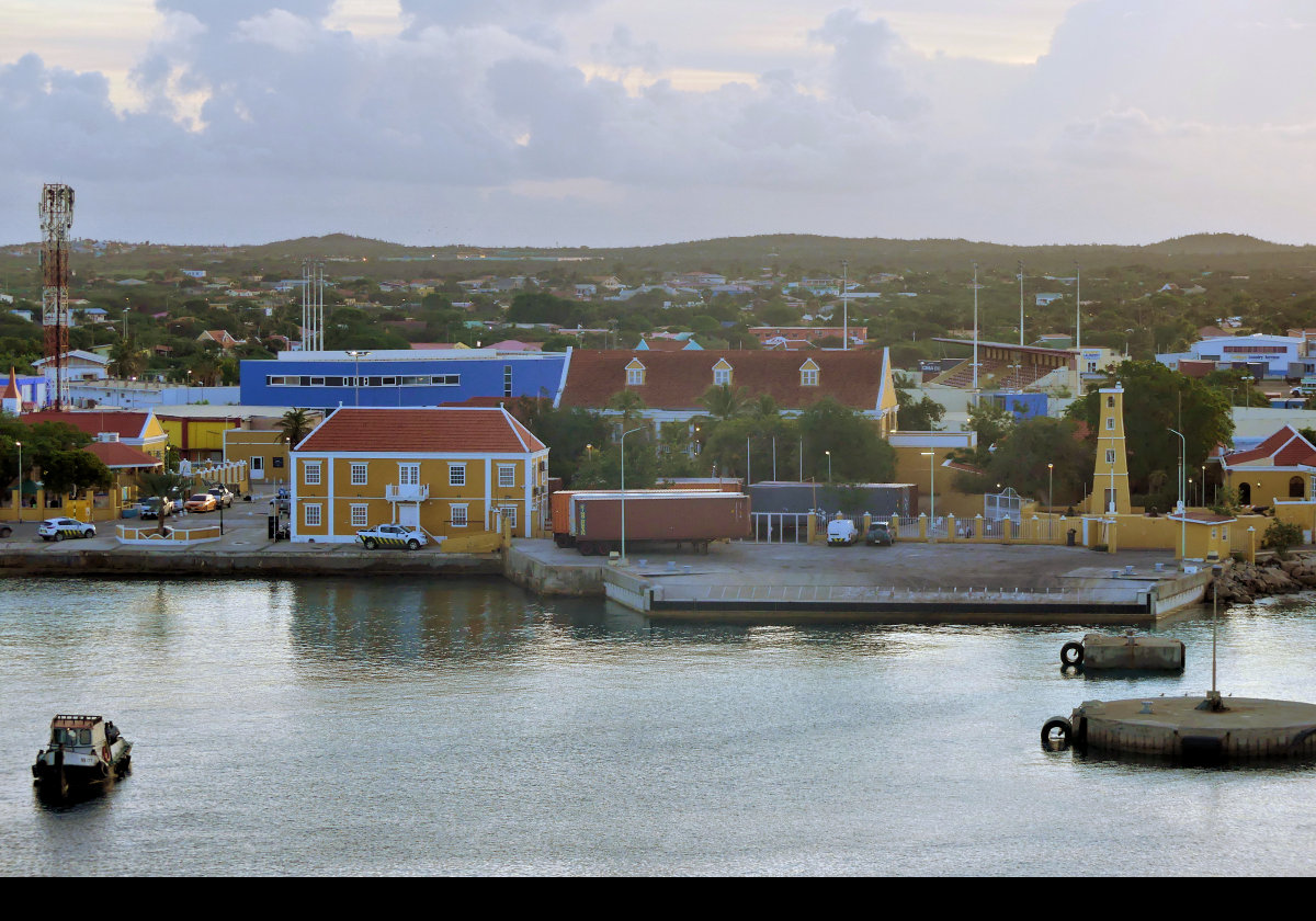 The building on the sea front to the left is the Cusroms Office; the tower is the lighthouse in Fort Oranje.